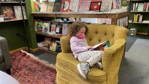 little girl reading in a bookshop